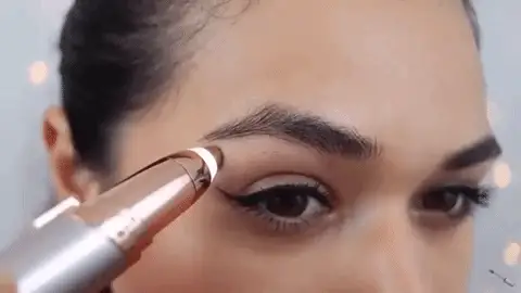 Close-up da caneta depiladora em uso na sobrancelha